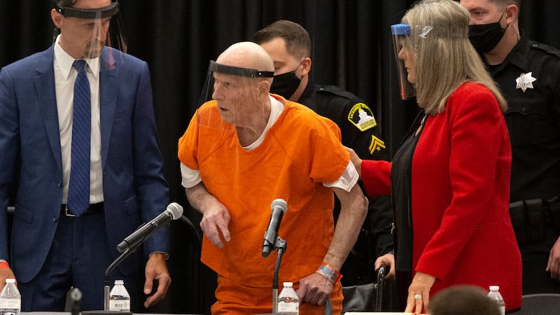Joseph James DeAngelo, center, charged with being the Golden State Killer, is helped up by his...